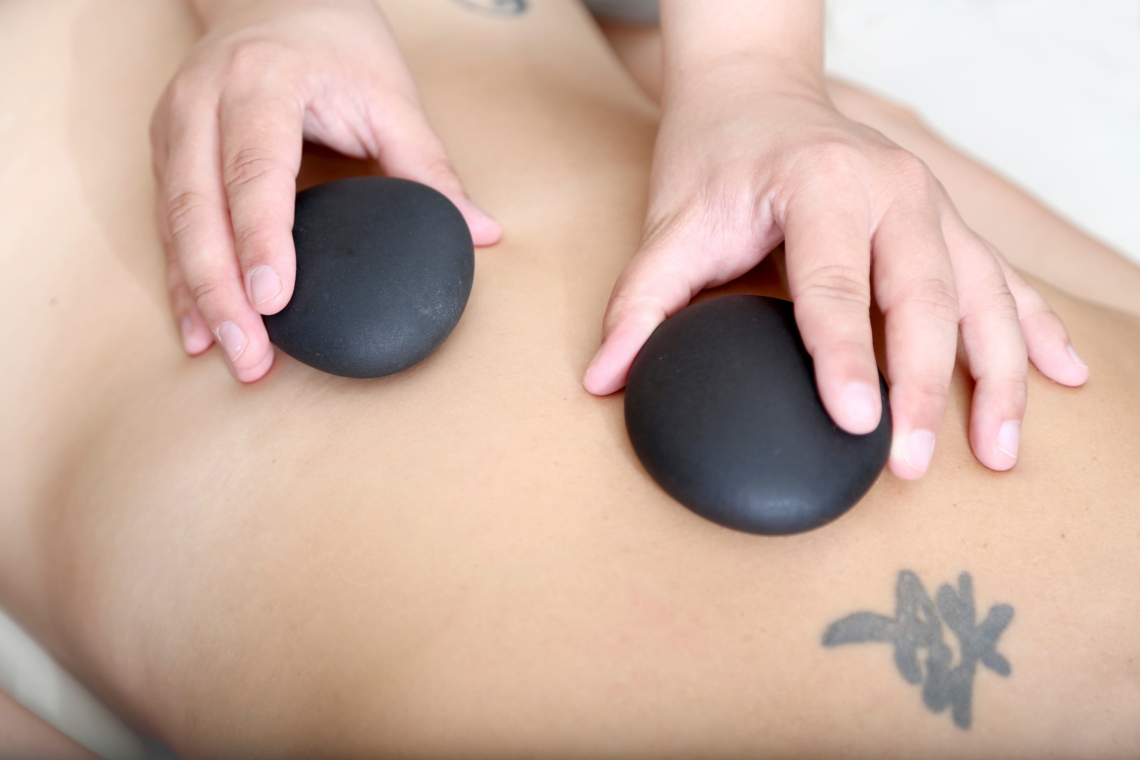 A therapist placing heated stones on a client's upper back