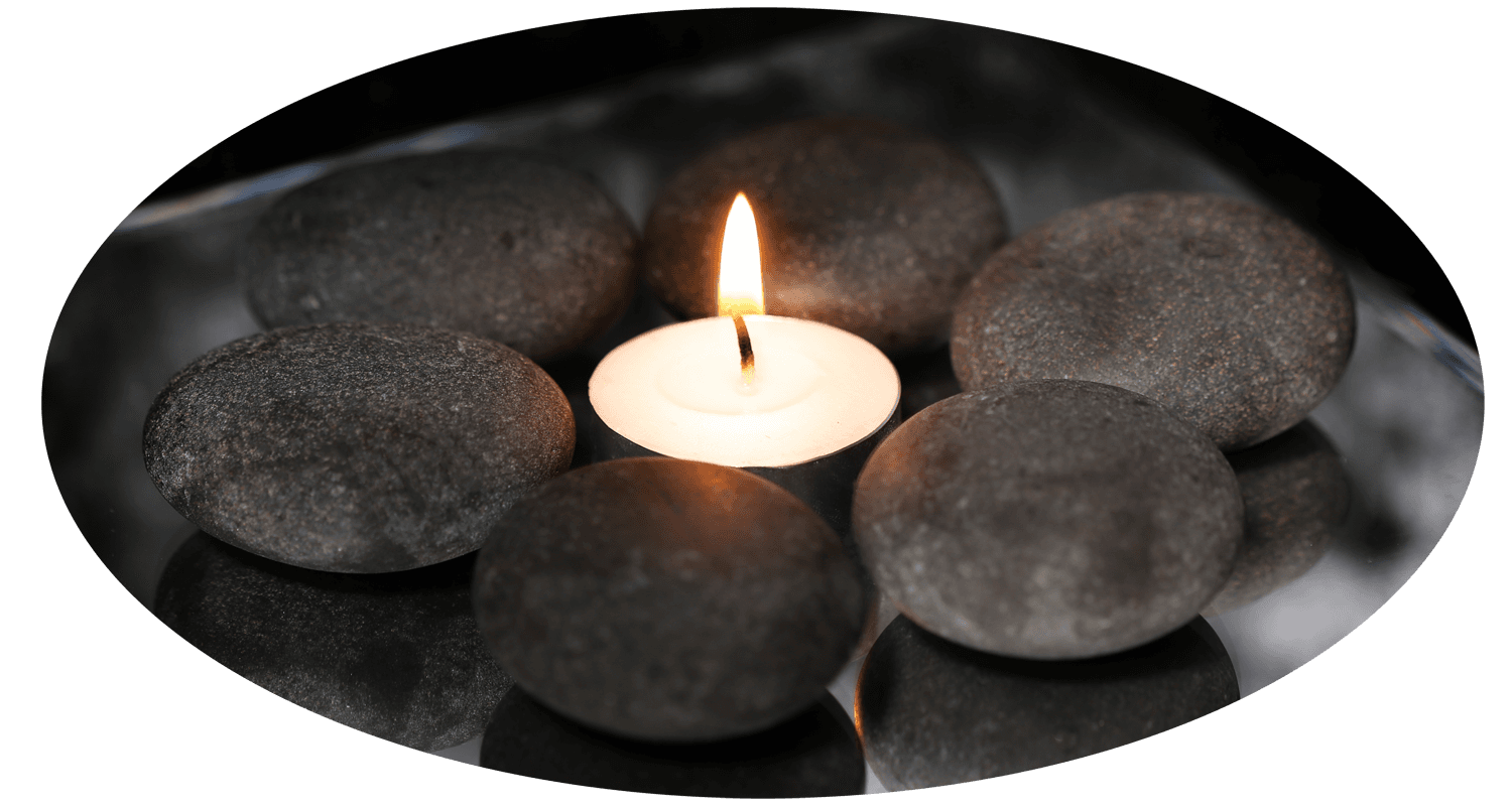 A stack of smooth massage stones topped with a small red flower