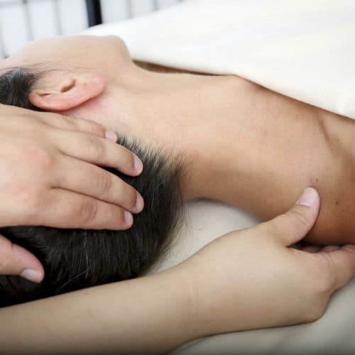 A therapist gently supporting a client's head and shoulder during a therapeutic massage