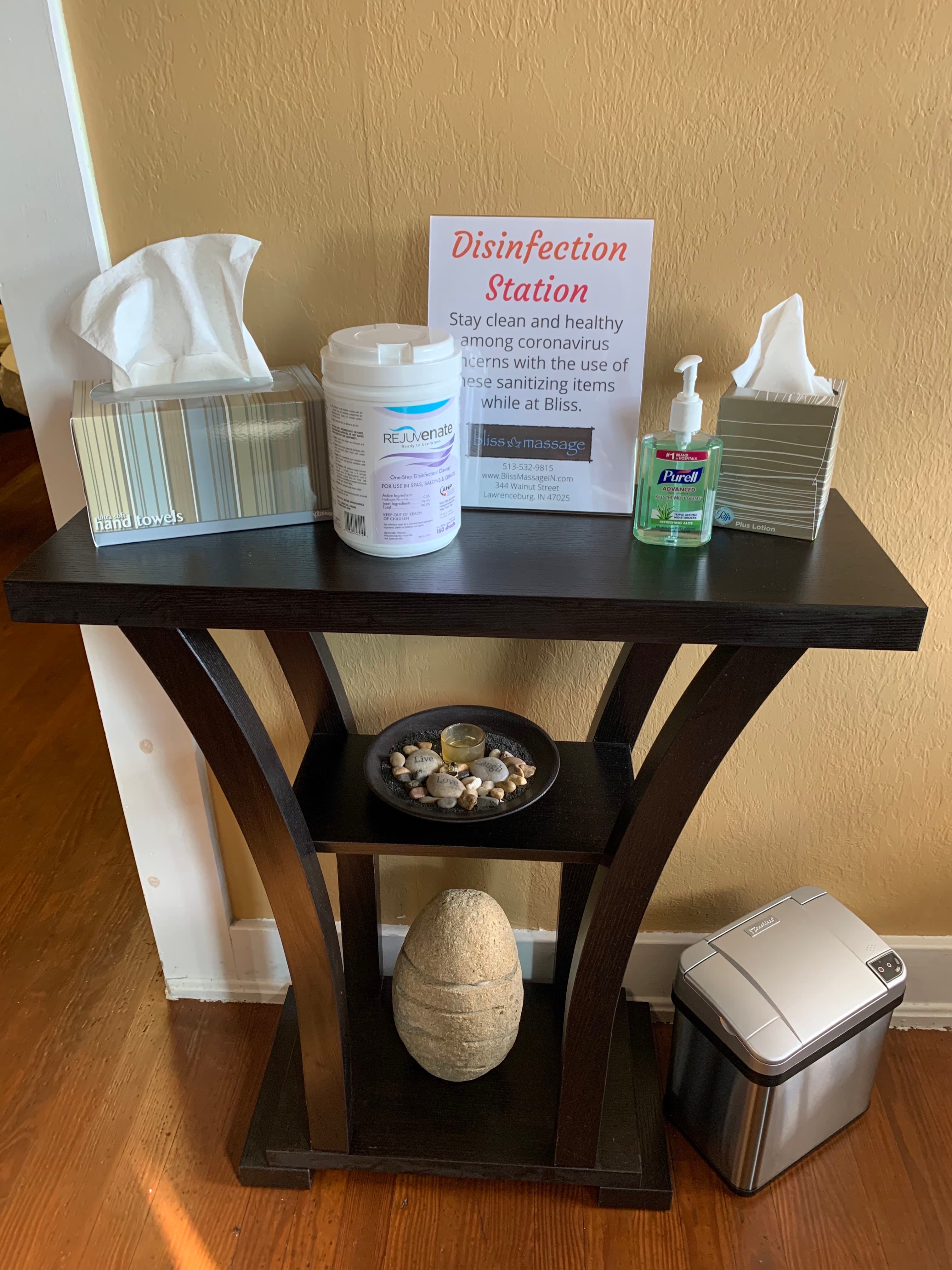 A disinfection station at Bliss Massage with hand sanitizer, tissues, and disinfecting wipes